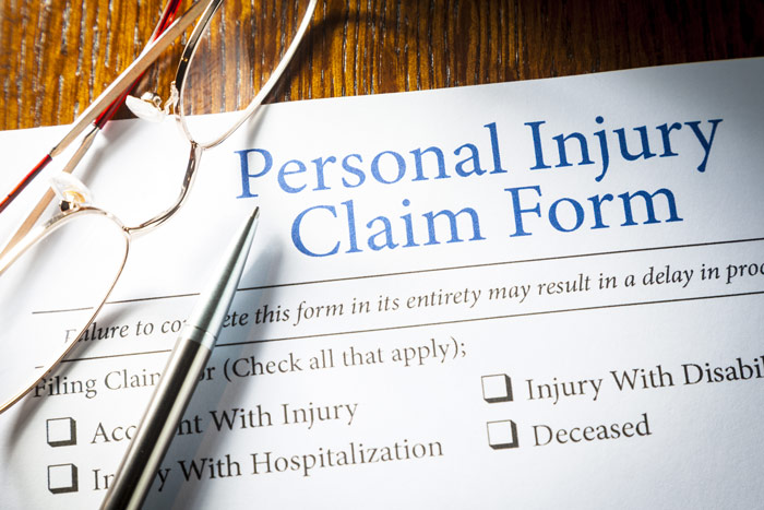 closeup of a personal injury claim form with reading glasses and a silver pen