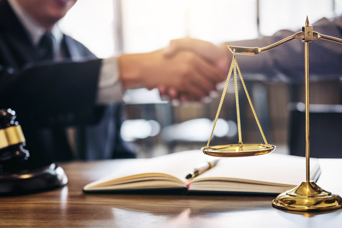 two men shaking hands in front of a set of scales and a gavel