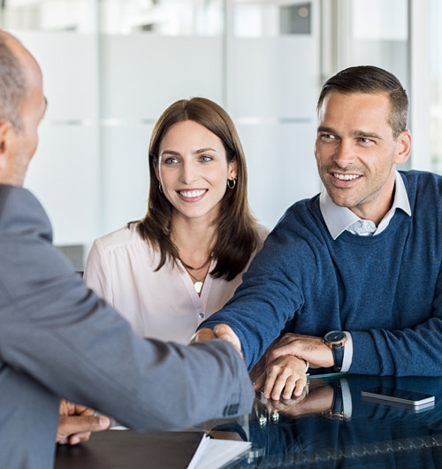 middle aged couple across the table from a man in a suit, the two men are shaking hands