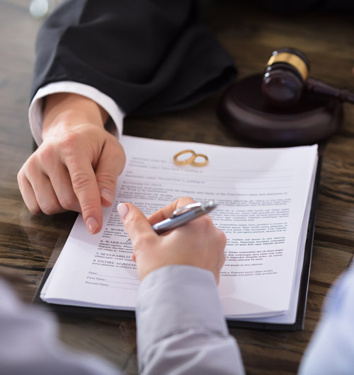 women signing a piece of paper with two wedding rings on top of it