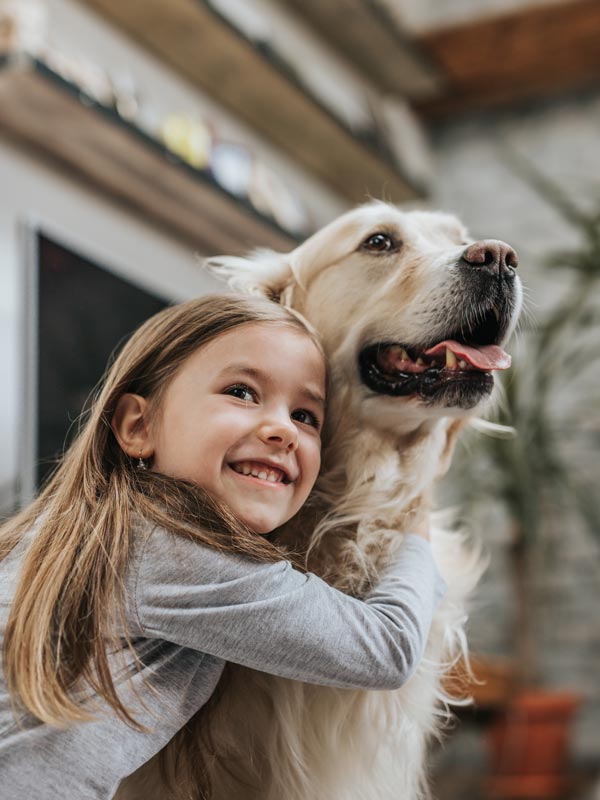 little girl hugging golden retriever